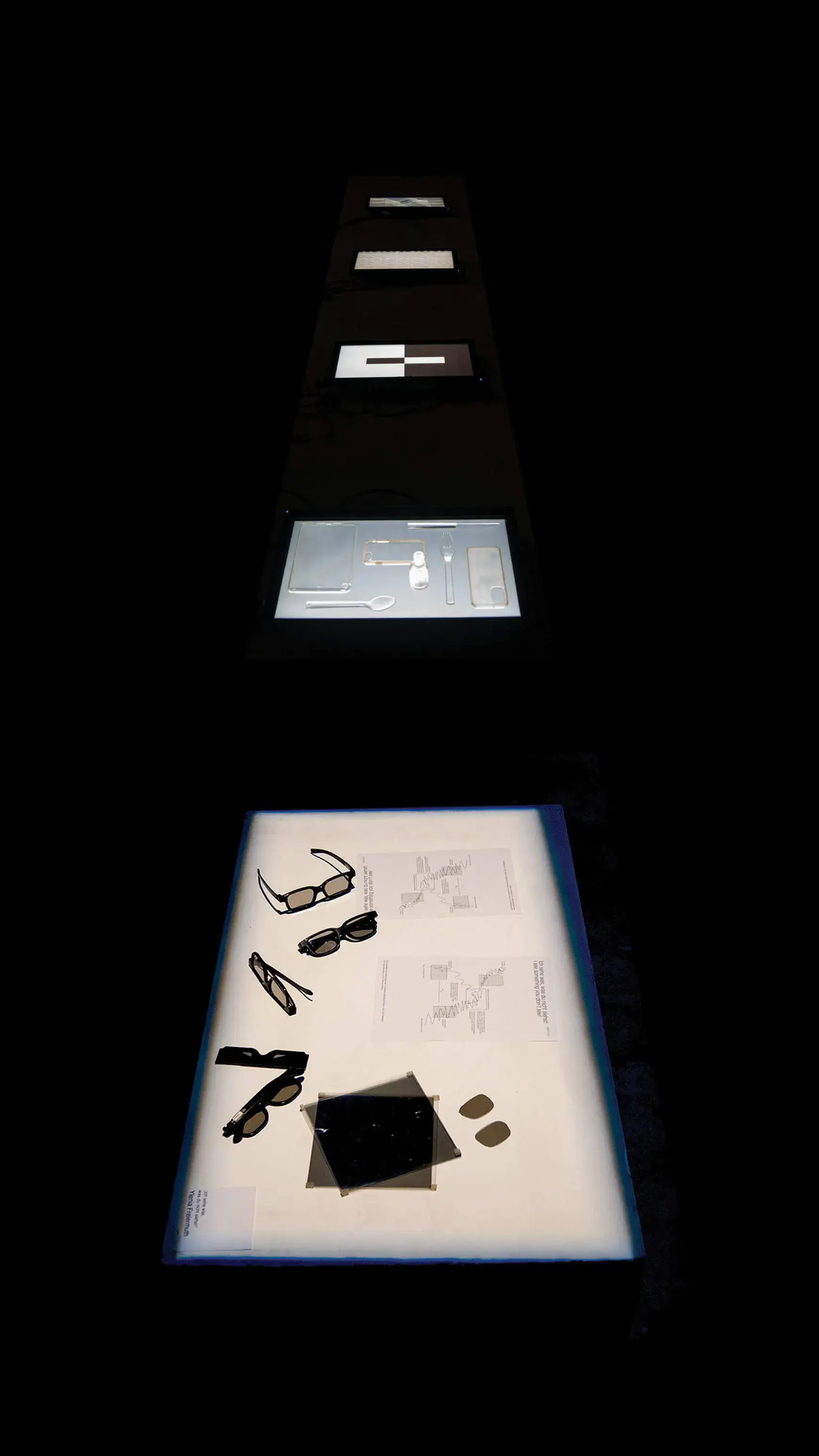 transparente Objekte in einer Ausstellung auf weisser Fläche in dunkelm Raum