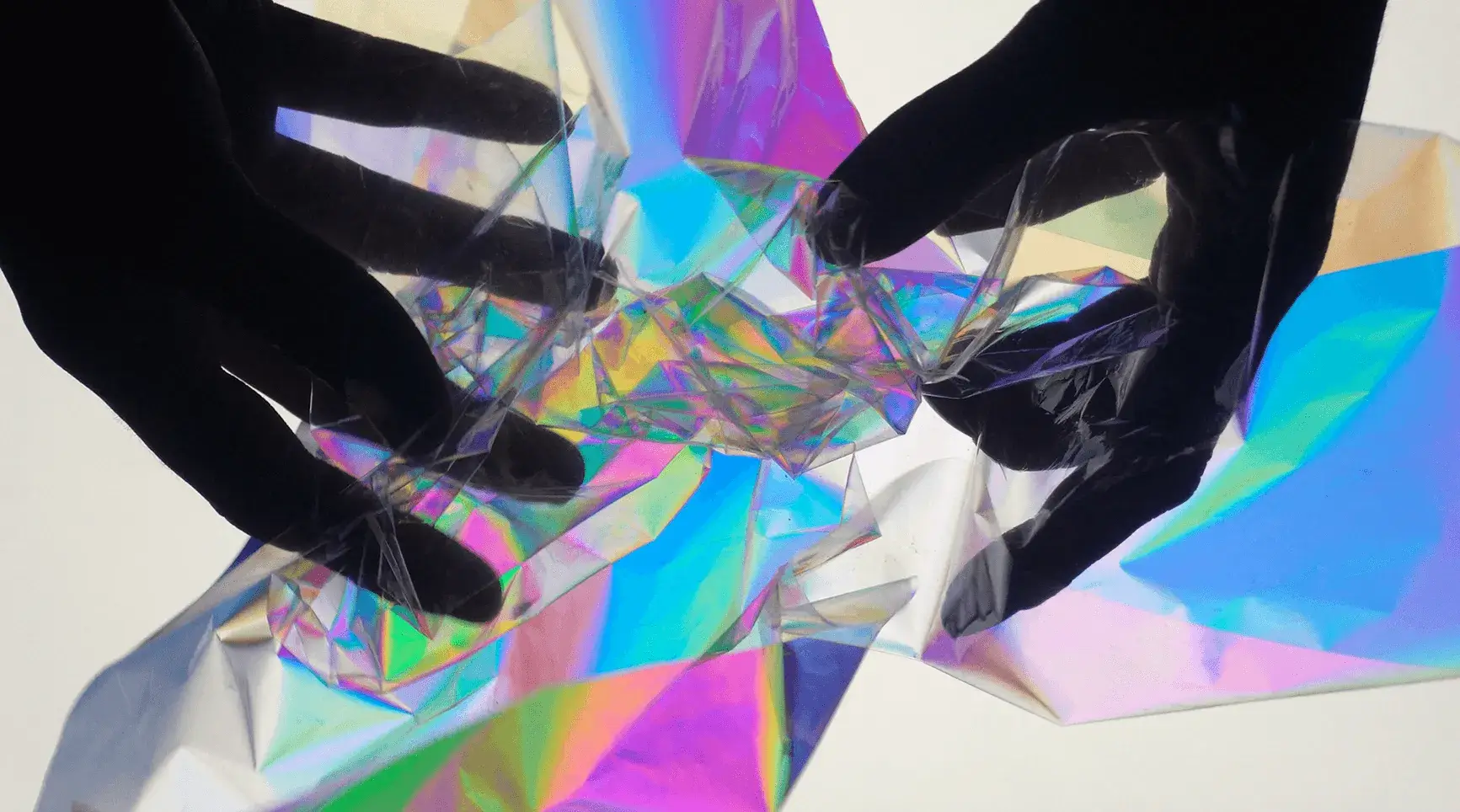 zwei Hände, die eine Kunststofffolie in bunten Farben drehen